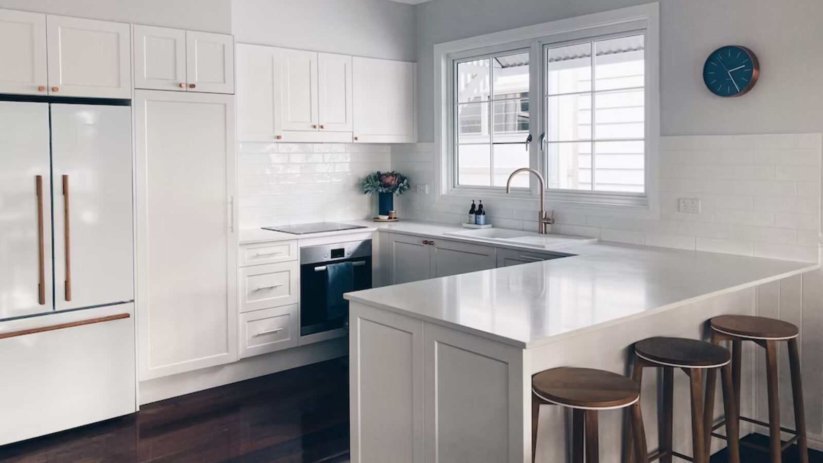 A home kitchen with white cabinets and dark hardwood flooring