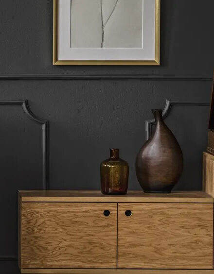 Charcoal painted wall with wood sideboard and vases